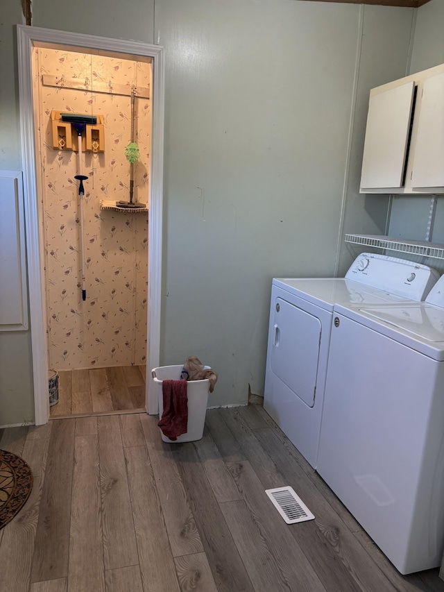 washroom with hardwood / wood-style floors, cabinets, and independent washer and dryer