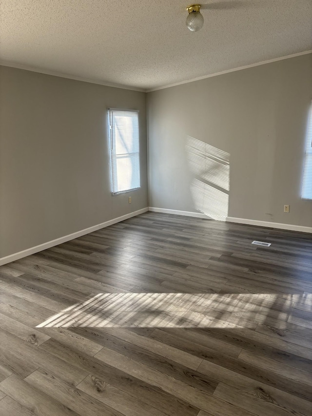 spare room with ornamental molding, a textured ceiling, and dark wood-type flooring