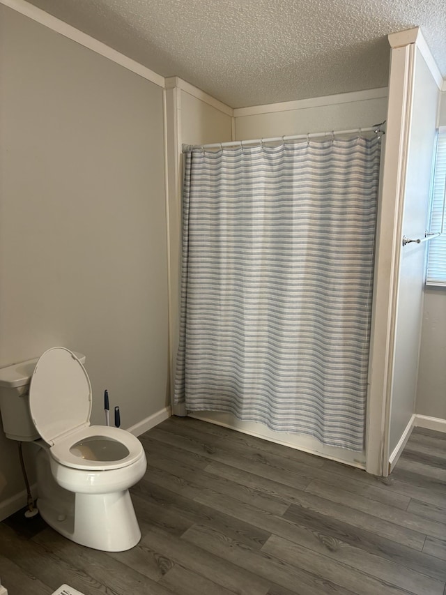 bathroom with crown molding, hardwood / wood-style floors, a textured ceiling, and toilet