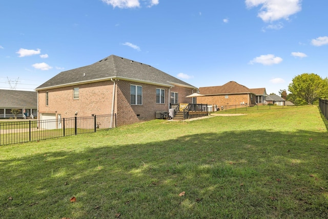 rear view of house featuring a garage, a deck, and a lawn