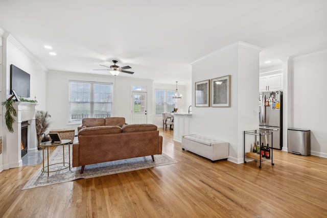 living room with ornamental molding, light hardwood / wood-style floors, and ceiling fan