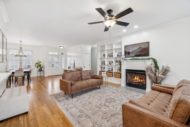 living room with crown molding, ceiling fan with notable chandelier, and light hardwood / wood-style floors