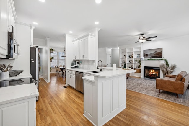 kitchen with sink, kitchen peninsula, white cabinets, and appliances with stainless steel finishes