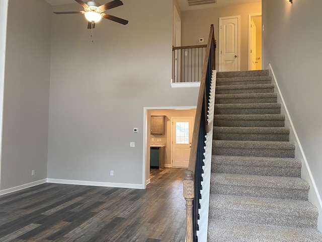 stairway with hardwood / wood-style floors, ceiling fan, and a towering ceiling