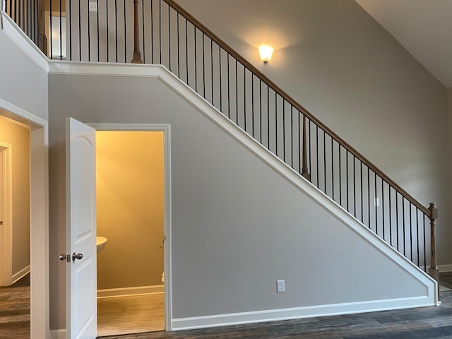 stairway with wood-type flooring and high vaulted ceiling