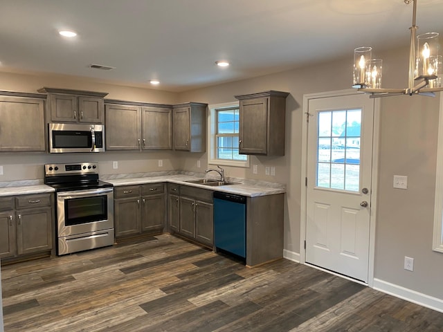 kitchen with dark hardwood / wood-style flooring, a chandelier, sink, and stainless steel appliances