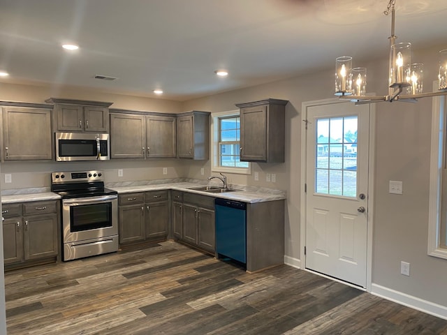 kitchen featuring sink, an inviting chandelier, dark hardwood / wood-style floors, pendant lighting, and appliances with stainless steel finishes