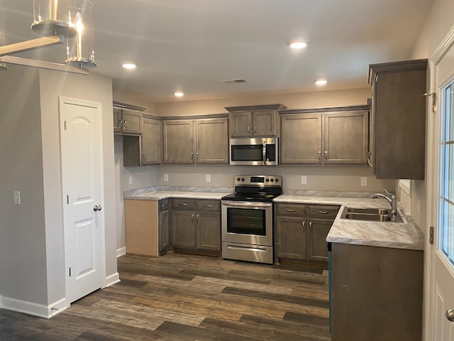 kitchen with dark hardwood / wood-style flooring, sink, light stone countertops, and stainless steel appliances