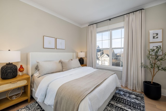 bedroom featuring hardwood / wood-style flooring, crown molding, and multiple windows