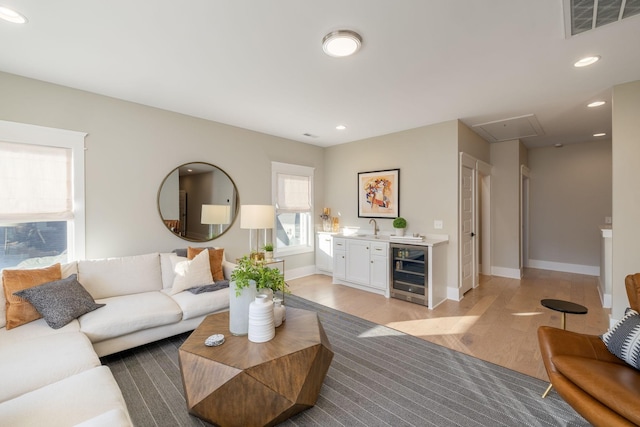 living room with wet bar, light hardwood / wood-style floors, and beverage cooler