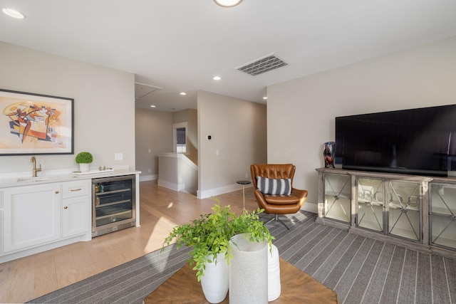 living room with wine cooler, indoor wet bar, and light wood-type flooring