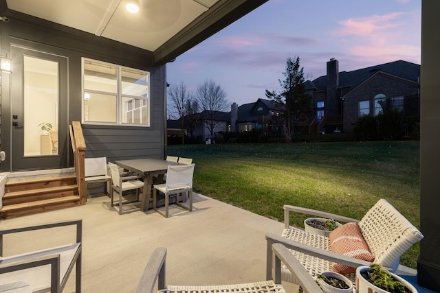 patio terrace at dusk featuring a lawn