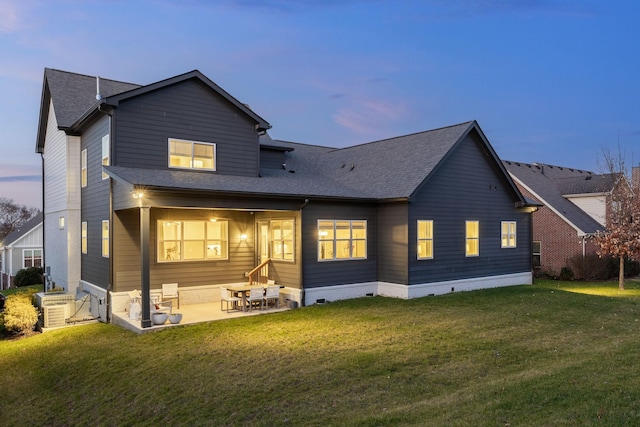 back house at dusk with a yard and a patio area