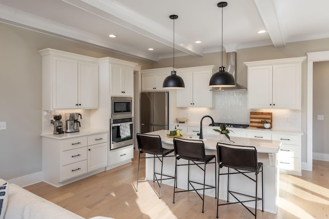 kitchen featuring tasteful backsplash, white cabinets, stainless steel appliances, wall chimney range hood, and beam ceiling