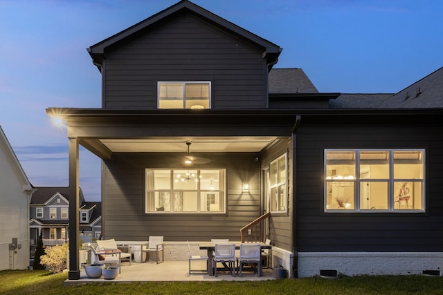 back house at dusk with a yard and a patio area