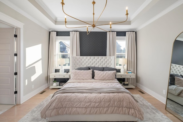 bedroom with crown molding, a tray ceiling, a chandelier, and light wood-type flooring