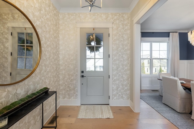 foyer entrance with crown molding and light hardwood / wood-style flooring