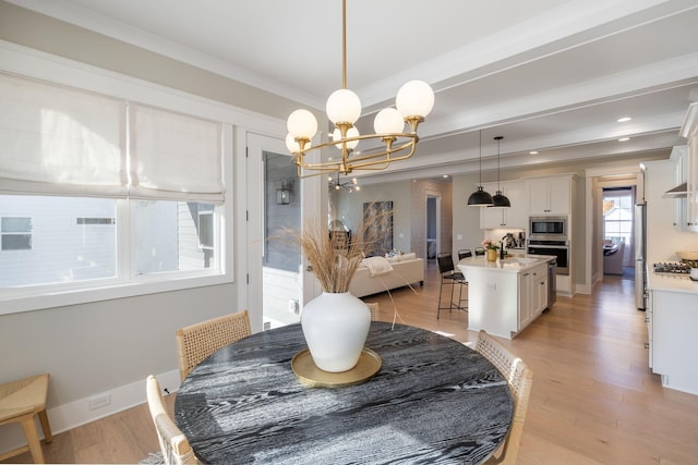 dining room with a notable chandelier, ornamental molding, sink, and light wood-type flooring