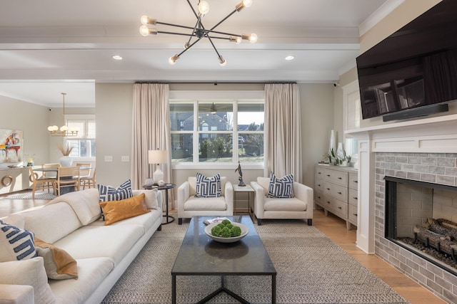 living room with an inviting chandelier, ornamental molding, and light hardwood / wood-style floors