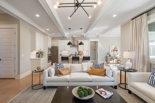 living room featuring beamed ceiling, sink, a chandelier, crown molding, and light hardwood / wood-style flooring