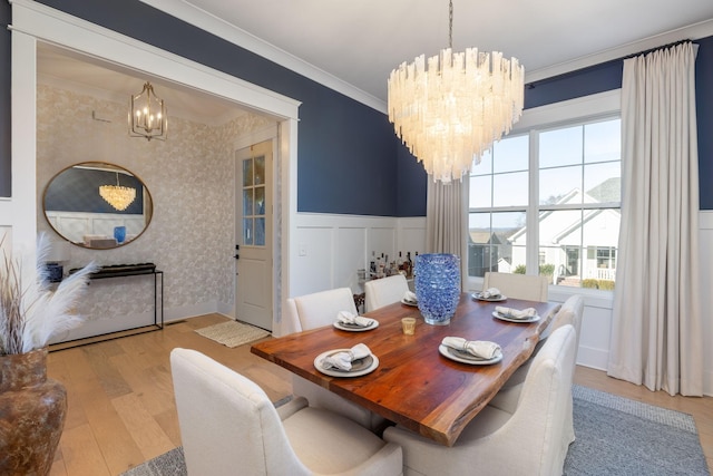 dining area featuring crown molding, light wood-type flooring, and an inviting chandelier