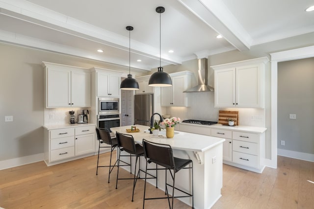 kitchen featuring appliances with stainless steel finishes, white cabinetry, tasteful backsplash, beamed ceiling, and wall chimney exhaust hood