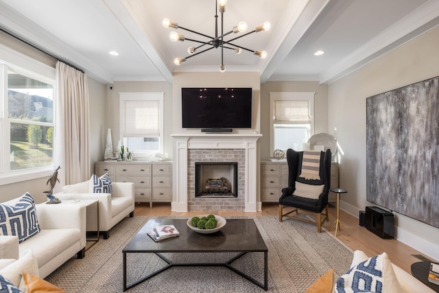 living room with crown molding, a chandelier, beamed ceiling, a fireplace, and light hardwood / wood-style floors