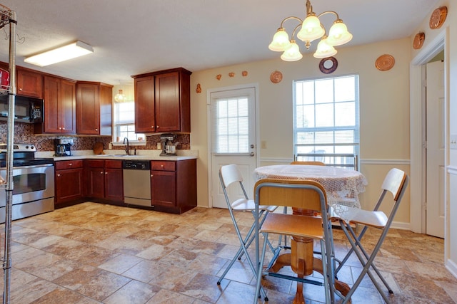 kitchen with a healthy amount of sunlight, a chandelier, stainless steel appliances, and decorative light fixtures