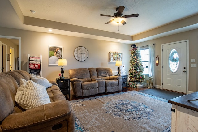 living room featuring a raised ceiling and ceiling fan