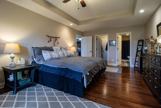 bedroom featuring a walk in closet, connected bathroom, a tray ceiling, and ceiling fan