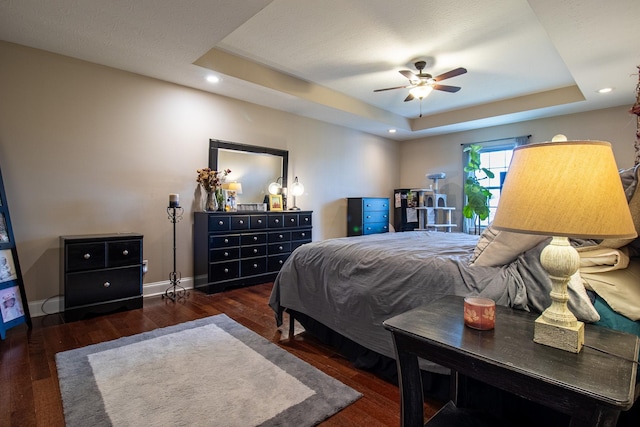 bedroom featuring a raised ceiling, ceiling fan, and dark hardwood / wood-style floors