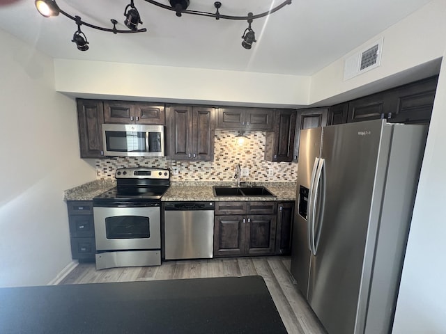 kitchen with sink, light wood-type flooring, tasteful backsplash, dark brown cabinets, and stainless steel appliances