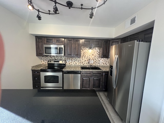 kitchen featuring dark brown cabinets, backsplash, stainless steel appliances, and sink