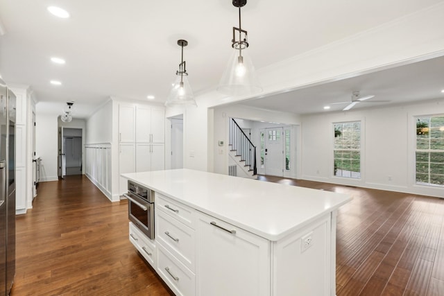 kitchen with stainless steel oven, a kitchen island, dark hardwood / wood-style flooring, pendant lighting, and white cabinets