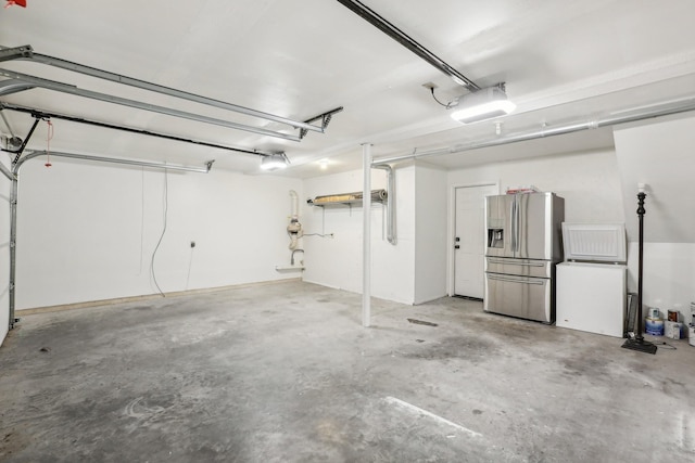 garage with stainless steel fridge with ice dispenser and a garage door opener