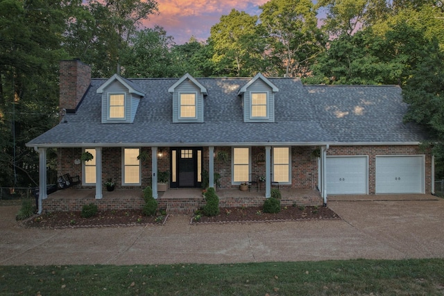 cape cod home with covered porch and a garage