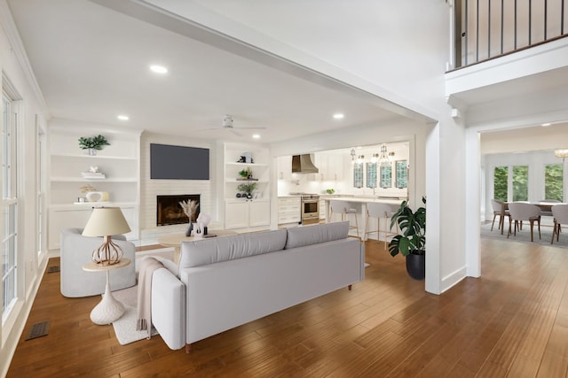 living room with ceiling fan, a fireplace, dark wood-type flooring, and built in features