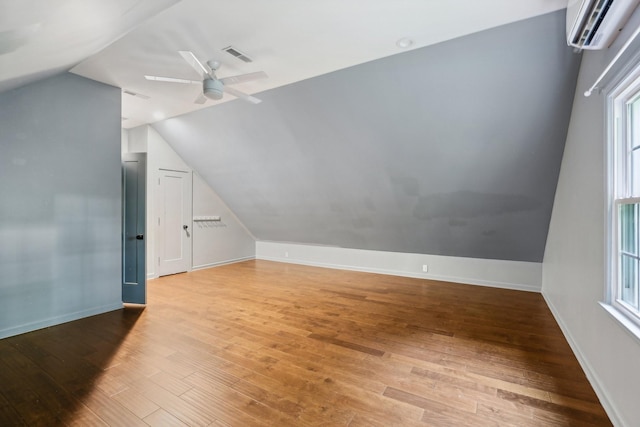 bonus room featuring a wall mounted air conditioner, hardwood / wood-style flooring, ceiling fan, and lofted ceiling