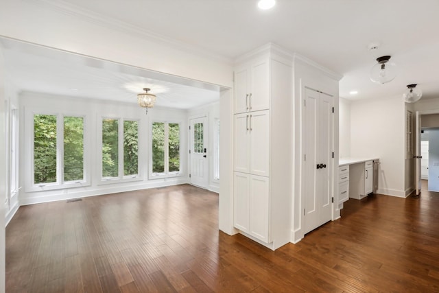 hallway with plenty of natural light, dark hardwood / wood-style floors, crown molding, and an inviting chandelier