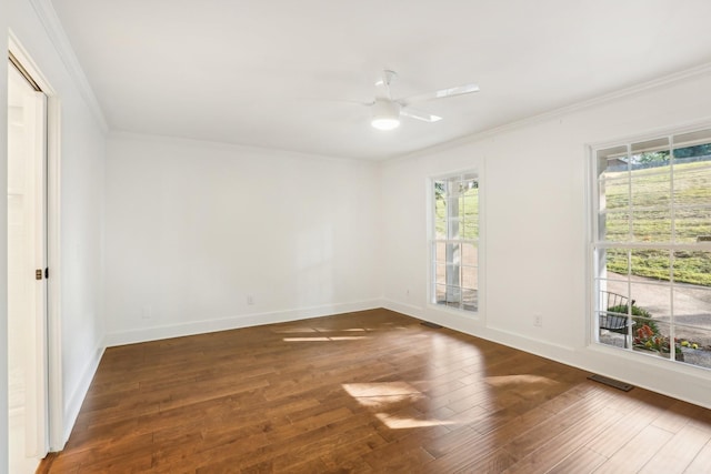 empty room featuring ceiling fan, crown molding, dark wood-type flooring, and a wealth of natural light