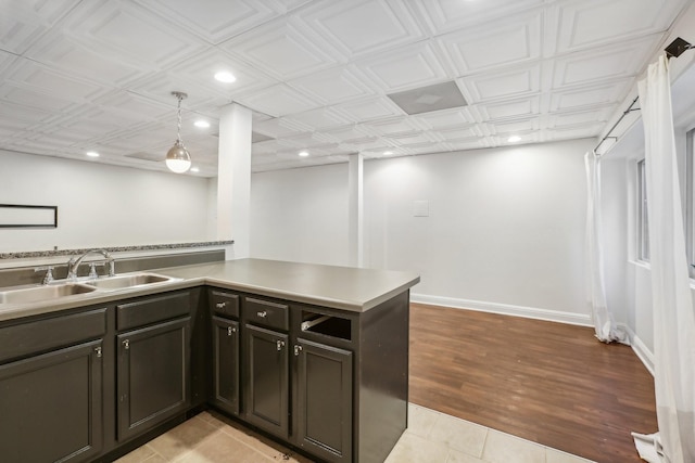 kitchen featuring light tile patterned flooring, kitchen peninsula, sink, and hanging light fixtures