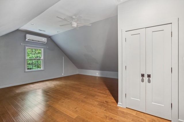 bonus room featuring a wall mounted air conditioner, lofted ceiling, ceiling fan, and wood-type flooring