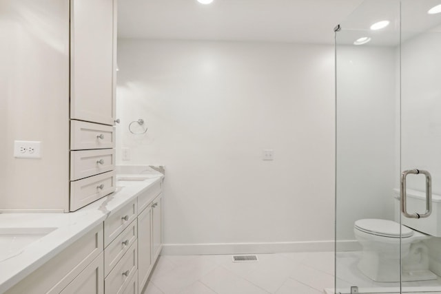 bathroom featuring tile patterned flooring, vanity, a shower with shower door, and toilet