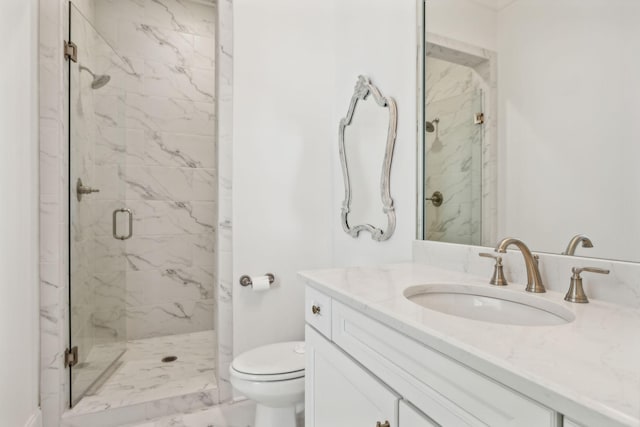 bathroom featuring a shower with door, vanity, and toilet