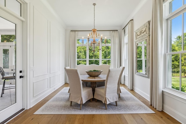 dining area with hardwood / wood-style flooring, ornamental molding, and a notable chandelier