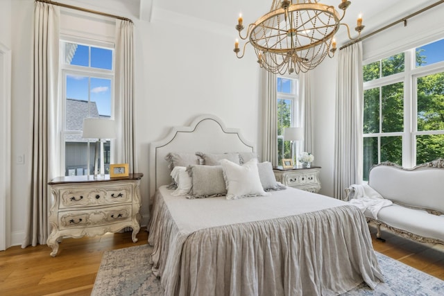 bedroom with hardwood / wood-style floors, a notable chandelier, crown molding, and multiple windows