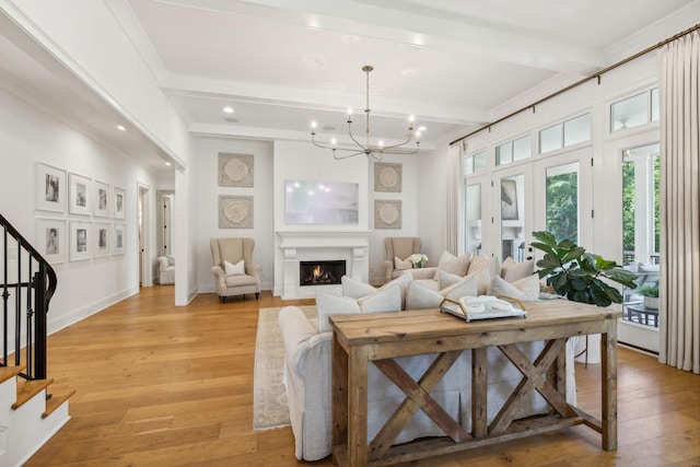 living room featuring beam ceiling, an inviting chandelier, light wood-type flooring, and french doors