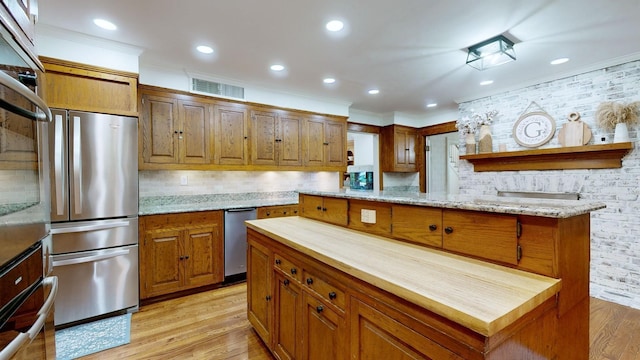 kitchen featuring a kitchen island, light wood-type flooring, backsplash, and stainless steel refrigerator