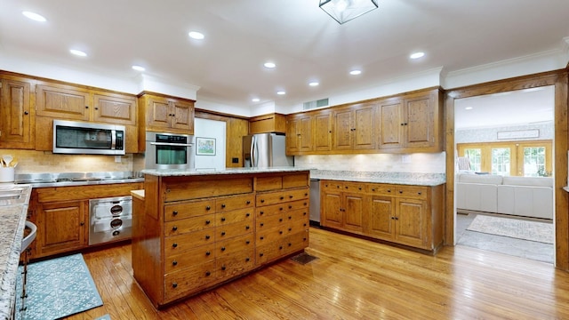 kitchen with light stone countertops, a center island, light wood-type flooring, and appliances with stainless steel finishes