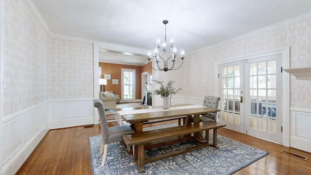 dining room with hardwood / wood-style floors, an inviting chandelier, french doors, and ornamental molding